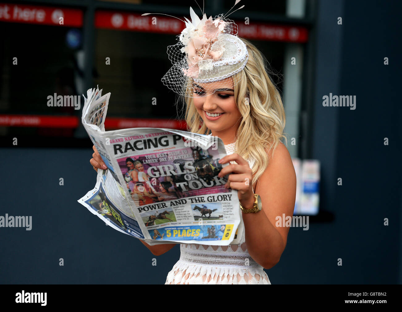 Eine weibliche Rennfahrerin liest die Racing Post während des Ladies Day des Crabbie's Grand National Festivals auf der Aintree Racecourse, Liverpool. Stockfoto