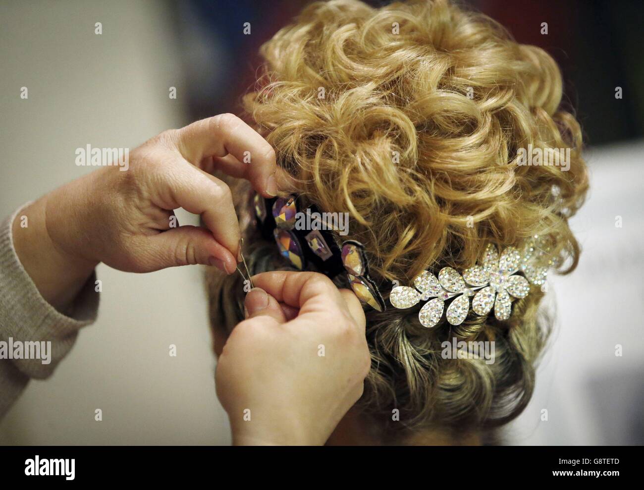 Eine Frau trägt bei, die Haare eines Teilnehmers während der Irish Dancing Championships in der Royal Concert Hall in Glasgow zu stylen. Stockfoto