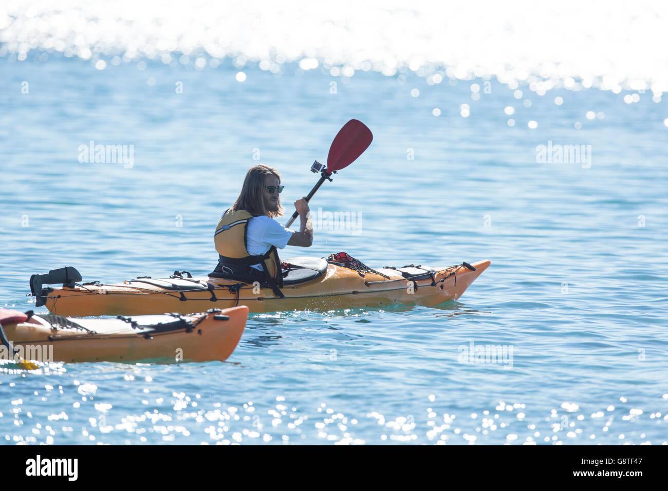 Mitte erwachsener Mann Kajak am Fluss bei strahlendem Sonnenschein Stockfoto