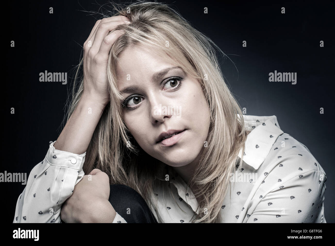 Junge Frau, die ängstlich mit Kopf in der hand Stockfoto