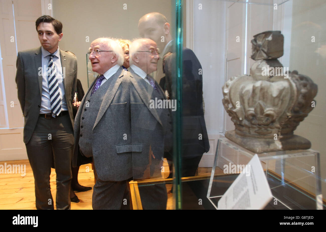 Präsident Michael D Higgins (Mitte) mit Simon Harris TD, dem Staatsminister der Finanzministerien (links), der bei der Eröffnung des neuen Besucherzentrums im Kilmainham Gaol, Dublin, am Königswappen des Gerichtsgebäudes vorbei geht. Stockfoto