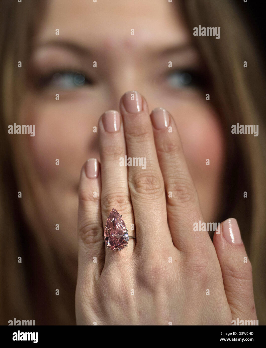 Ein Angestellter des Auktionshauses Sotheby's in London modelliert einen seltenen 'Fancy Vivid Pink' Diamanten namens 'Unique Pink', der im Mai in Genf zum Verkauf kommen wird, 15.38 Karat wiegt und voraussichtlich rund 28-38 Millionen Dollar einbringt. Stockfoto