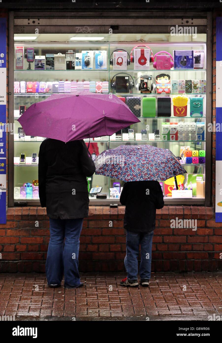 Fußgänger schauen in einen Gadget-Shop, während sie in einer April-Dusche im Stadtzentrum von Dublin gehen. Stockfoto