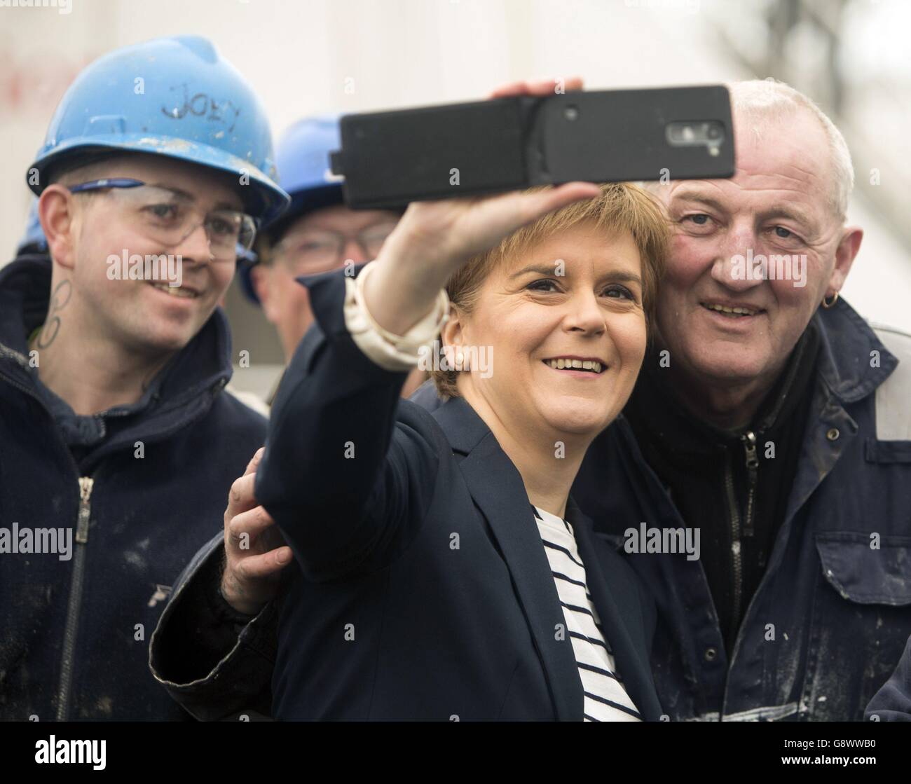 Nicola Sturgeon, die Vorsitzende der schottischen Nationalpartei, macht ein Selfie mit den Arbeitern während ihres Besuchs auf der Ferguson-Werft in Port Glasgow, während sie sich auf dem Weg des schottischen Wahlkampfs befindet. Stockfoto