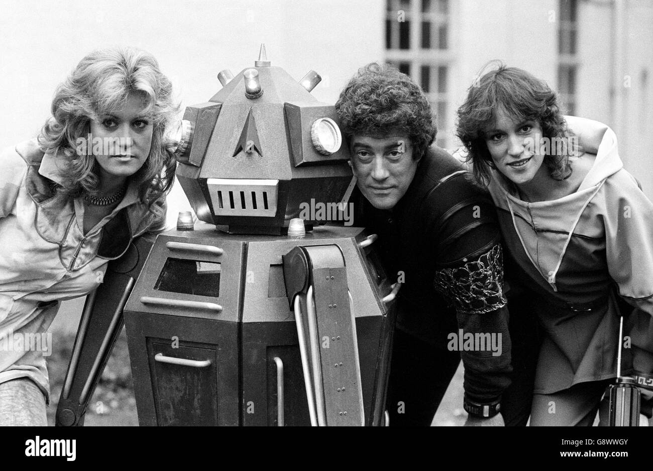 In den BBC TV Film Studios, Ealing Green, London, flankierten die Schauspielerinnen Sally Knyvette (l.) und Jan Chappell einen Roboter und Schauspieler Gareth Thomas, der Blake in Blakes 7, einem neuen 13-teiligen Weltraumabenteuer von Terry Nation, spielt. Stockfoto