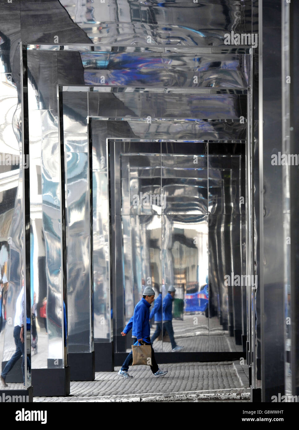 A man spaziert durch die neue Installation Reflect London von Covent  Garden, die 32,000 Quadratfuß Spiegel um die östliche Fassade des Market  Building in Covent Garden im Zentrum Londons wickelt und für