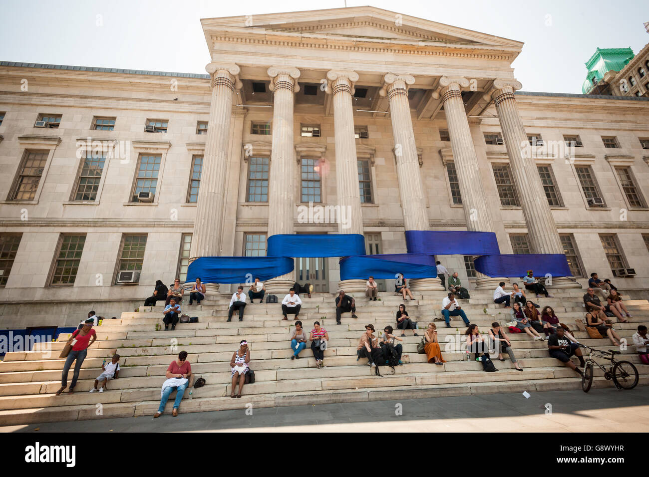 Büroangestellte auf ihre Mittagspause sitzen auf den Stufen des Brooklyn Borough Hall im New Yorker Stadtteil Brooklyn auf Freitag, 24. Juni 2016 vor den blauen Teil des ein Regenbogen-Band um das Gebäude zu Ehren des Gay Pride gewickelt. (© Richard B. Levine) Stockfoto