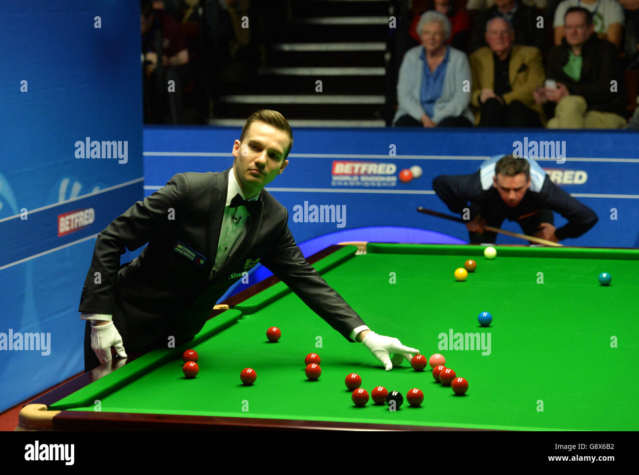 Schiedsrichter Marcel Eckhardt positioniert den roten Ball, den Alan McManus während des 11. Tages der Betfred Snooker-Weltmeisterschaft im Crucible Theatre, Sheffield, beobachtete. Stockfoto