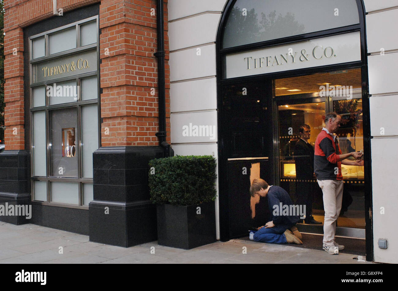 Arbeiter reparieren einen beschädigten Eingang bei Tiffany & Co Juwelieren in Sloane Square, London, der am Donnerstag, dem 6 2005. Oktober, einem Razzia-Raub ausgesetzt war. Ein mutmaßlicher Juwelendieb starb, nachdem er auf dem Cadogan-Platz von einem unmarkierten Polizeiauto nach einer Hochgeschwindigkeitsjagd überfahren worden war. Siehe PA Geschichte POLIZEI Tiffany. PRESSEFOTO DER VEREINIGUNG. Fiona Hanson/PA Stockfoto