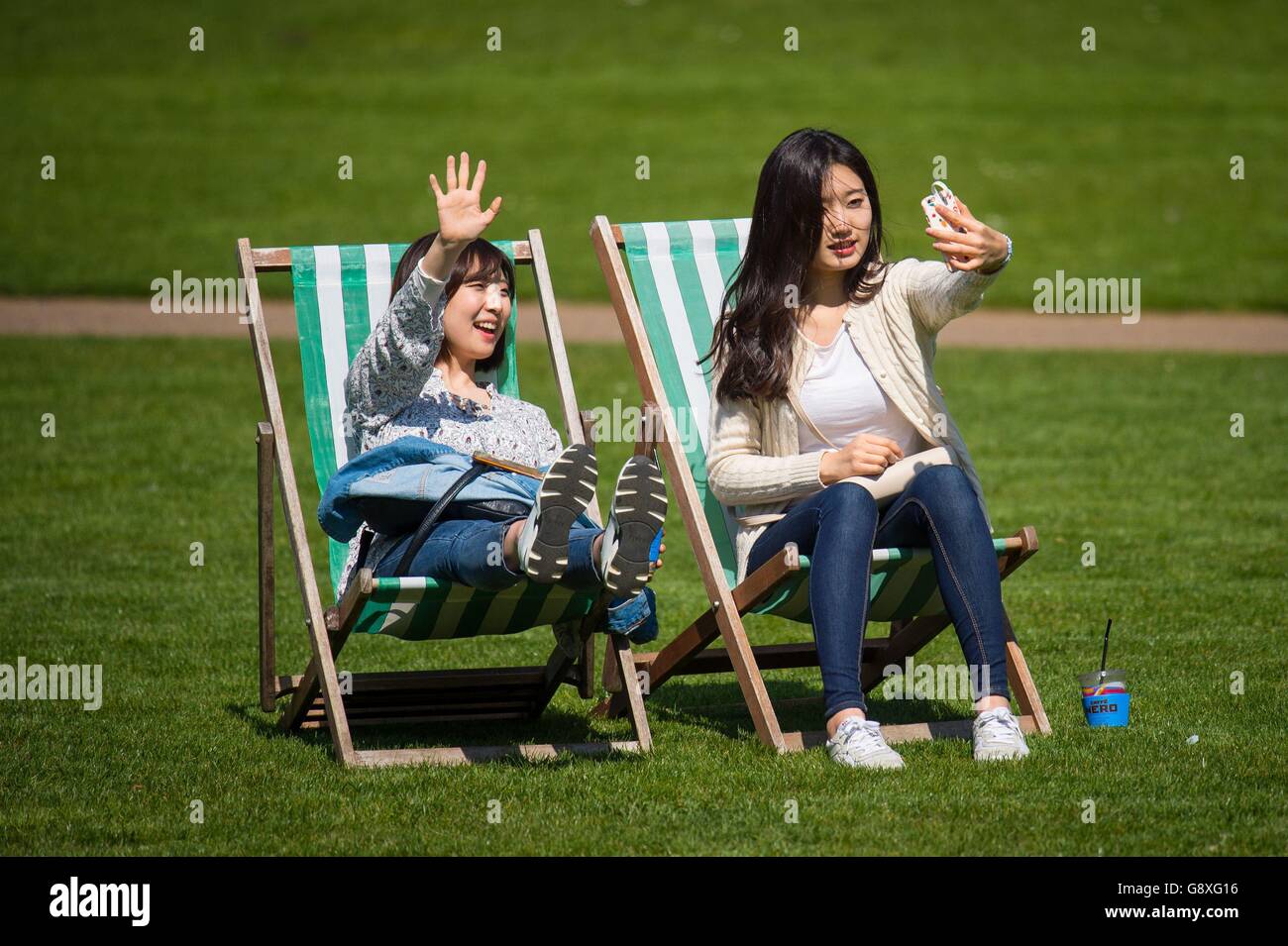 Zwei Frauen genießen die Sonne auf Liegestühlen im St James Park, London, da viele Teile des Vereinigten Königreichs einen Tag mit warmem Wetter genießen. Stockfoto