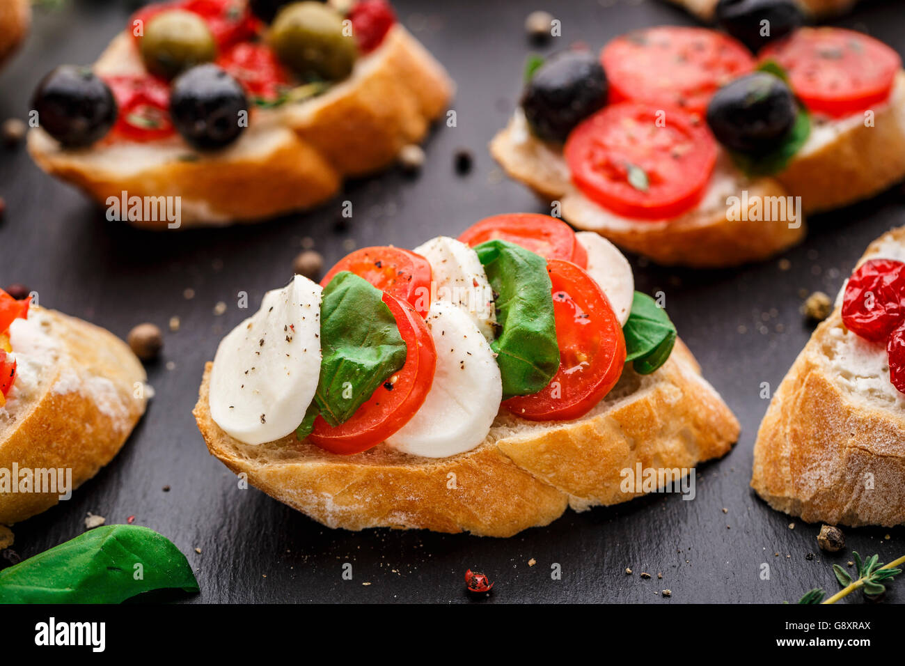 Italienische Bruschetta mit Tomaten, Mozzarella-Käse und Kräutern auf Schiefer Hintergrund Stockfoto