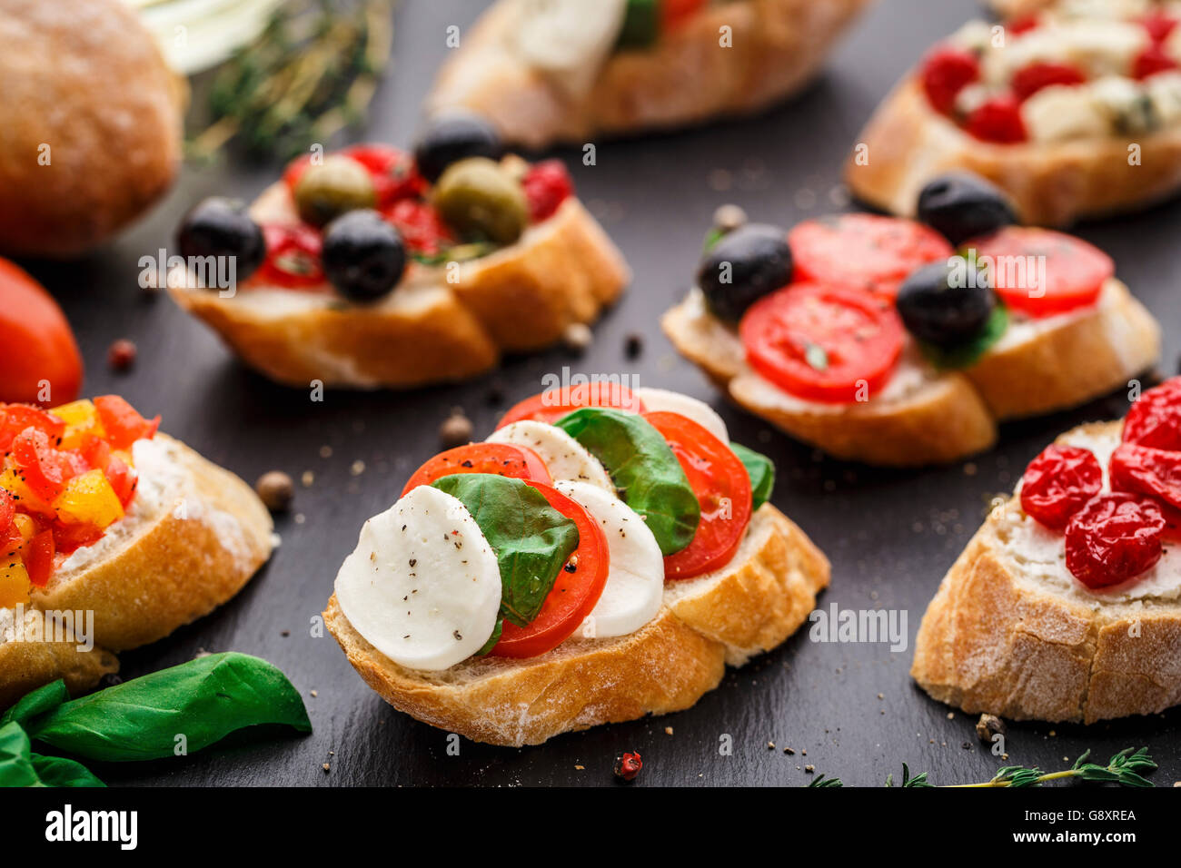 Italienische Bruschetta mit Tomaten, Mozzarella-Käse und Kräutern auf Schiefer Hintergrund Stockfoto