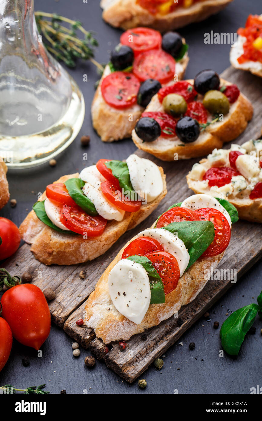 Italienische Bruschetta mit Tomaten, Mozzarella-Käse und Kräutern auf einem Holzbrett Stockfoto