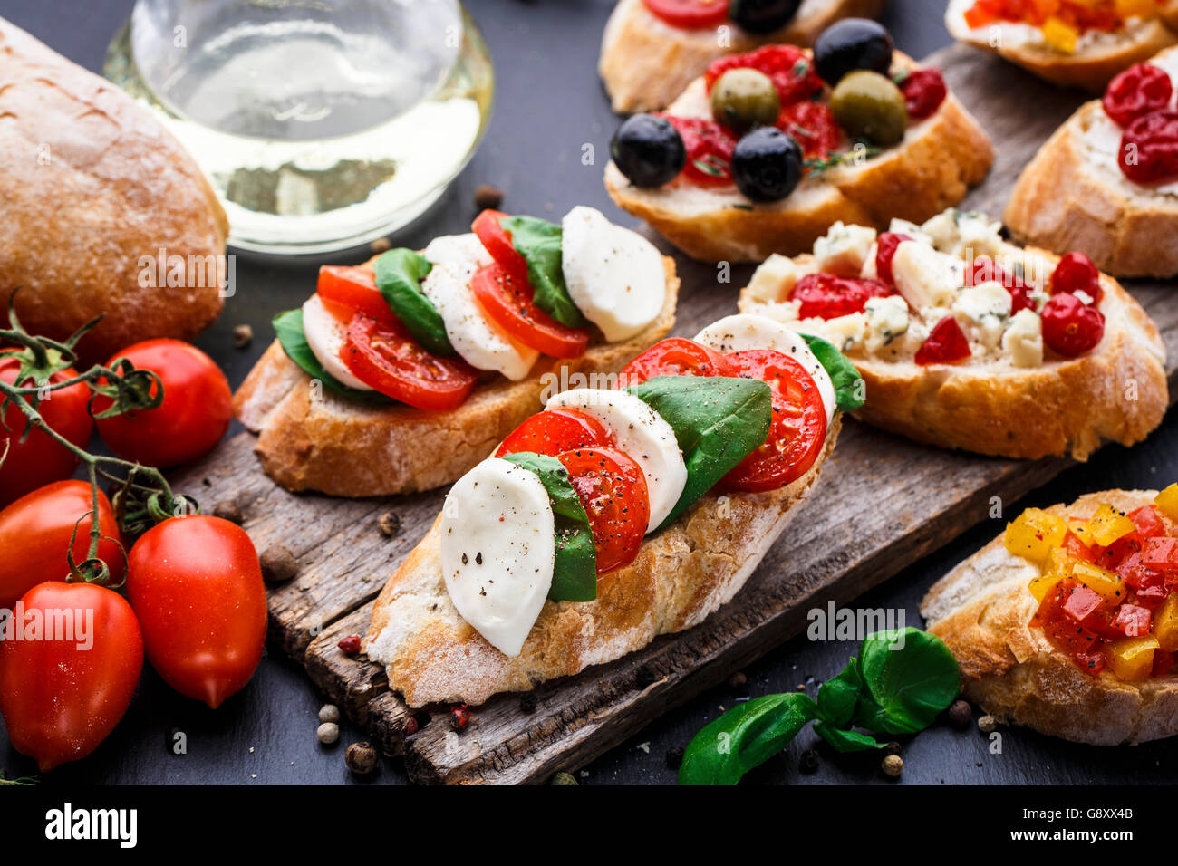 Italienische Bruschetta mit Tomaten, Mozzarella-Käse und Kräutern auf einem Holzbrett Stockfoto
