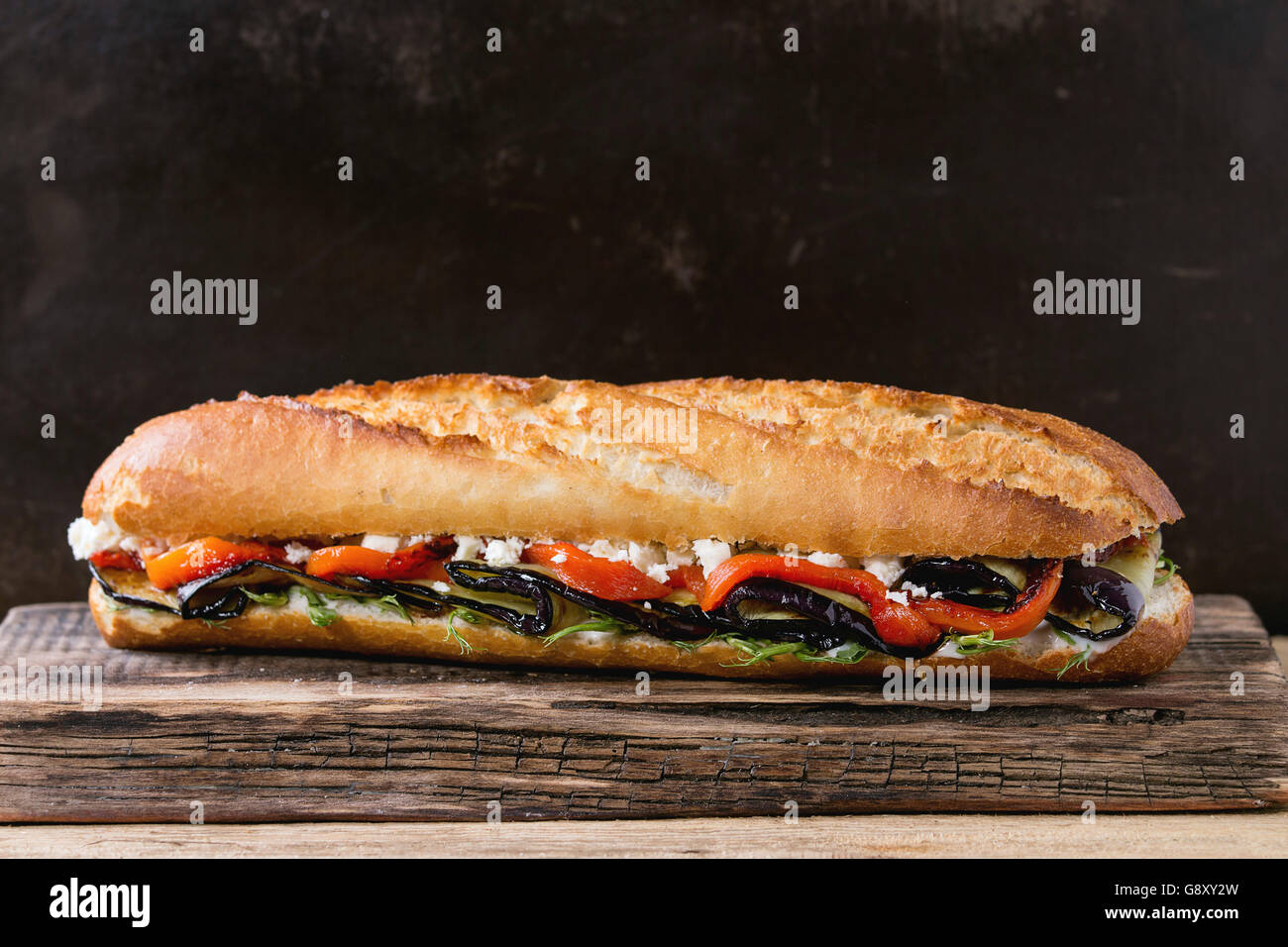 Vegetarische Baguette u-Boot-Sandwich mit gegrillter Aubergine, Paprika und Feta Käse auf hölzernen Schneidebrett über dunkle staatlich Stockfoto