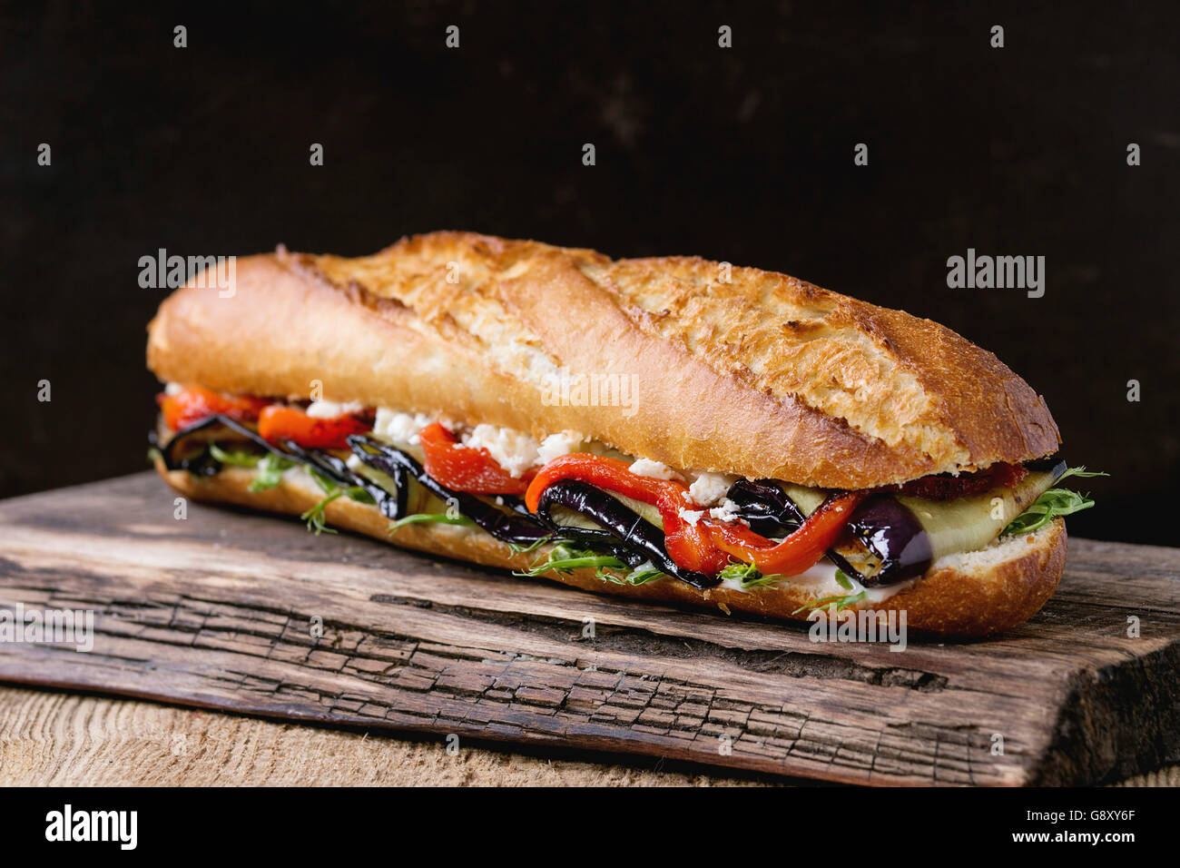 Vegetarische Baguette u-Boot-Sandwich mit gegrillter Aubergine, Paprika und Feta Käse auf hölzernen Schneidebrett über dunkle staatlich Stockfoto
