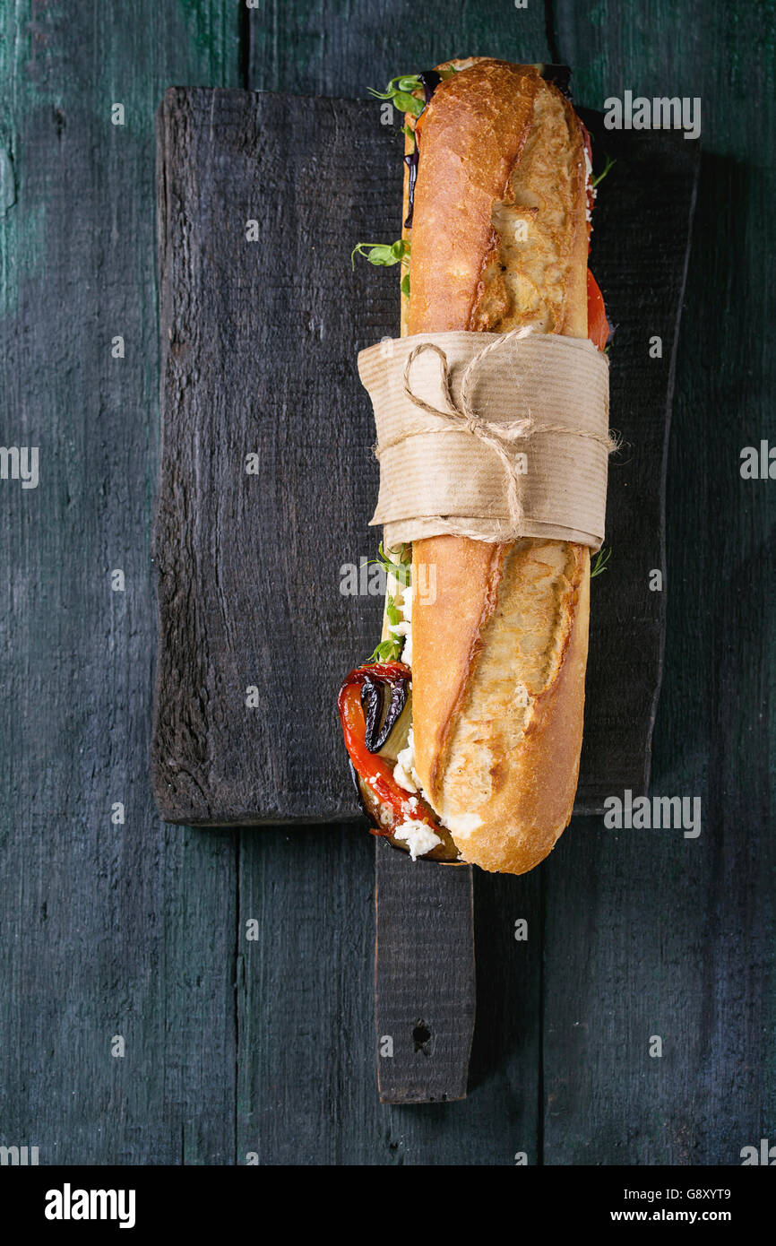 Tapezierte vegetarische Baguette u-Boot-Sandwich mit gegrillter Aubergine, Paprika und Feta Käse auf schwarzen Schneidbrett aus Holz über Stockfoto