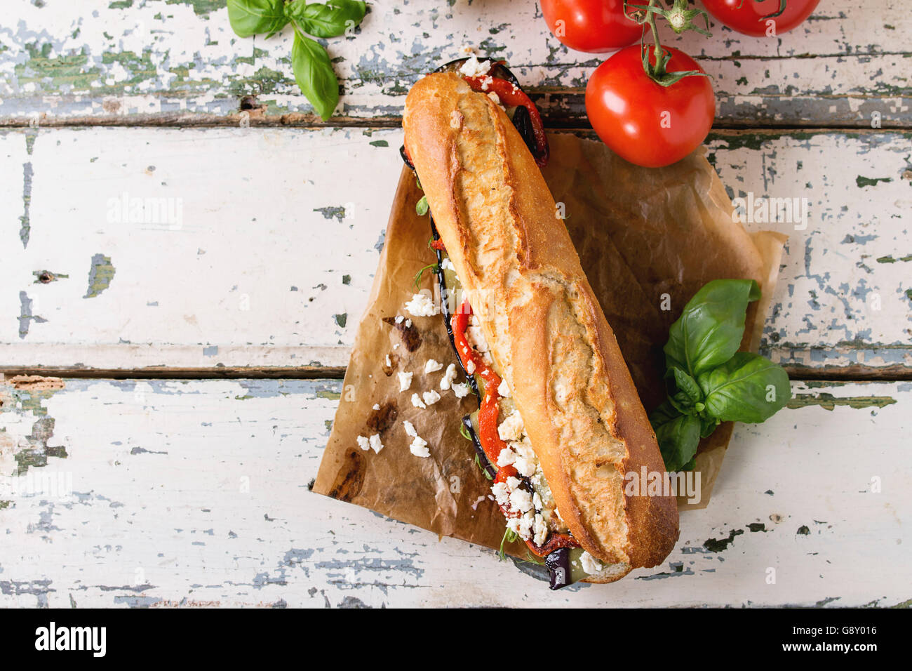 U-Boot-vegetarische Baguette-Sandwich mit gegrillter Aubergine, Paprika und Feta-Käse serviert auf Backpapier mit Tomaten und ol Stockfoto
