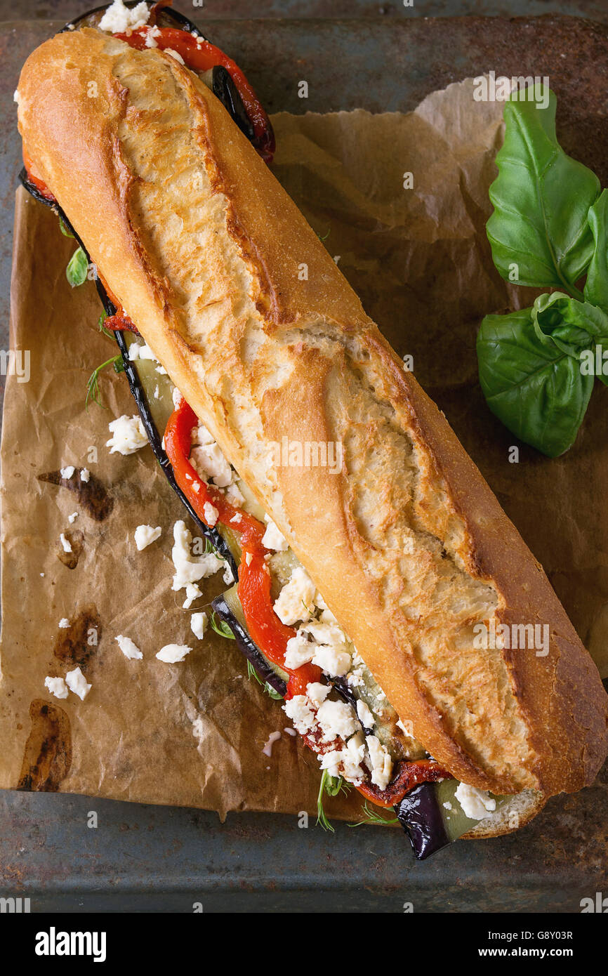 Vegetarische Baguette u-Boot-Sandwich mit gegrillter Aubergine, Paprika und Feta Käse auf Backpapier über dunkle rostigen strukturierte ba Stockfoto