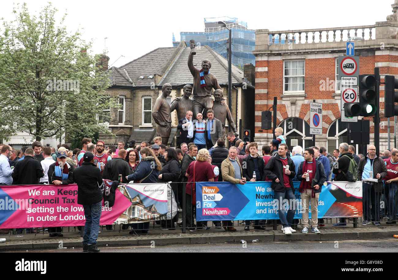 Fans versammeln sich um die Statue vor dem Upton Park mit Bobby Moore, Geoff Hurst, Ray Wilson und Martin Peters, die an Englands WM-Sieg 1966 vor dem Spiel der Barclays Premier League im Upton Park, London, erinnern. Stockfoto