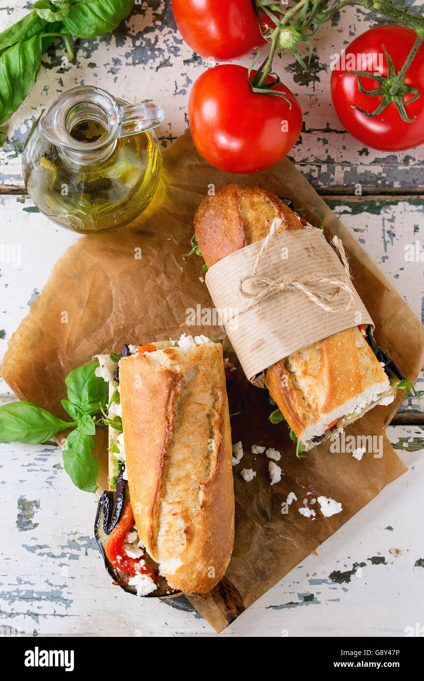 Zwei Hälfte vegetarische Baguette u-Boot-Sandwich mit gegrillter Aubergine, Paprika und Feta-Käse auf Backpapier mit Tom serviert Stockfoto