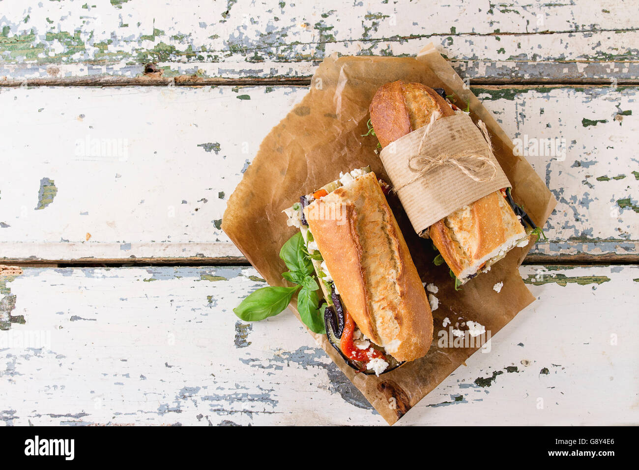 Zwei Hälfte vegetarische Baguette u-Boot-Sandwich mit gegrillter Aubergine, Paprika und Feta-Käse auf Backpapier über alte serviert Stockfoto