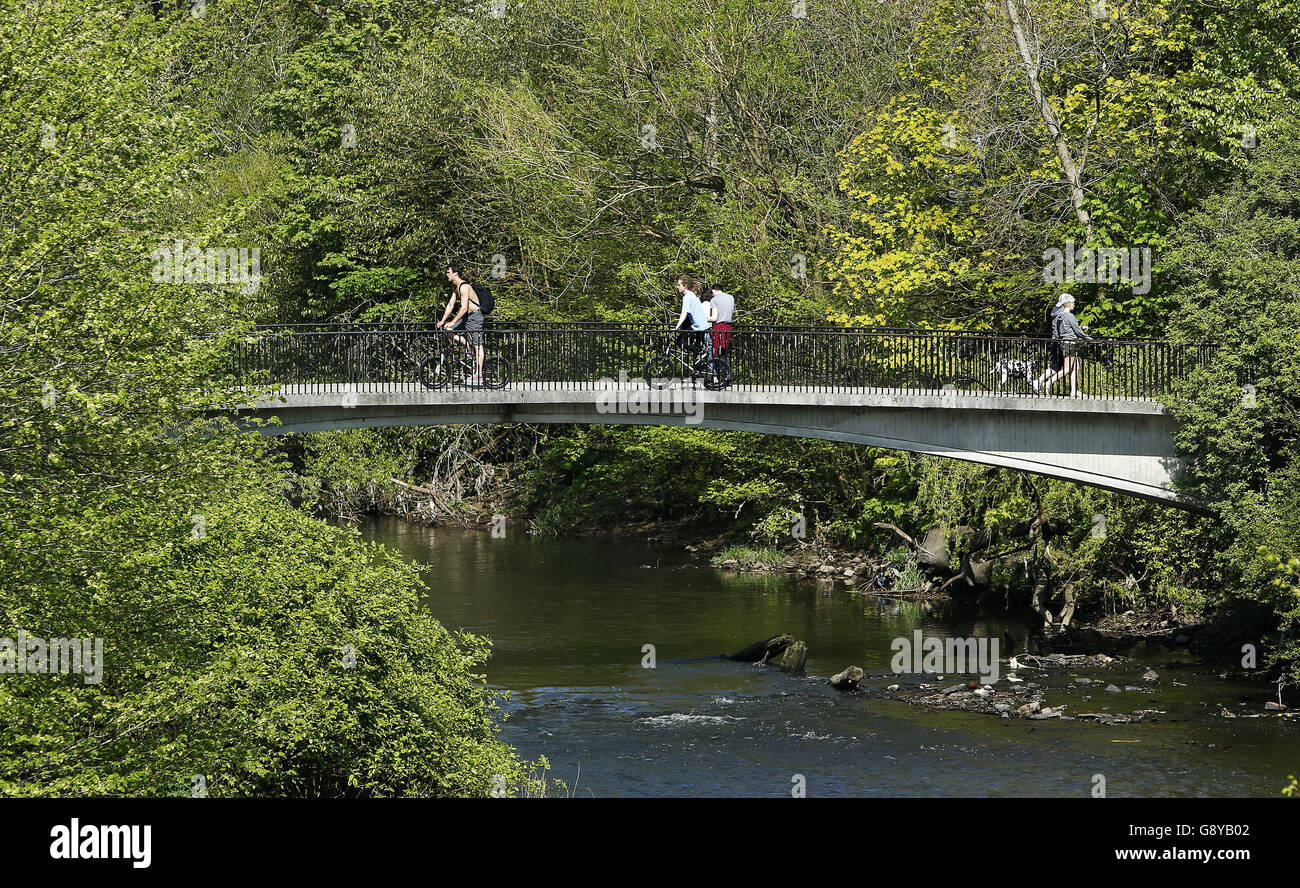 Im Kelvingrove Park in Glasgow fahren Menschen über eine Brücke über den Fluss Kelvin. Stockfoto