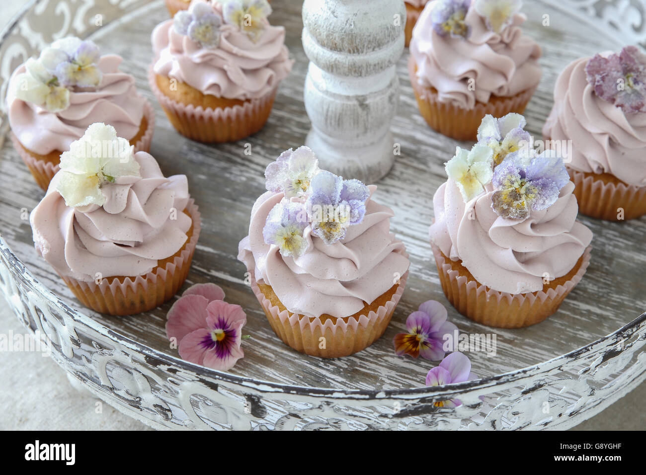 Lila Cupcakes mit gezuckerten essbare Blumen auf Vintage Etagere Stockfoto