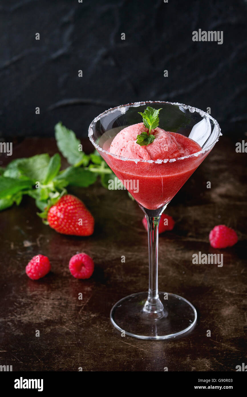 Cocktailglas Erdbeer Dessert mit Sorbet, serviert auf dunklem Hintergrund mit Erdbeeren, Himbeeren und Minze Behi gezuckert Stockfoto