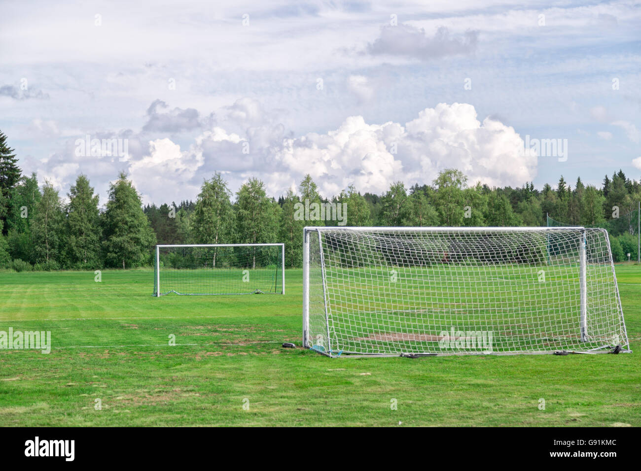 Fußballtore auf Fußballplatz mit bewölktem Himmel und Bäume. Stockfoto