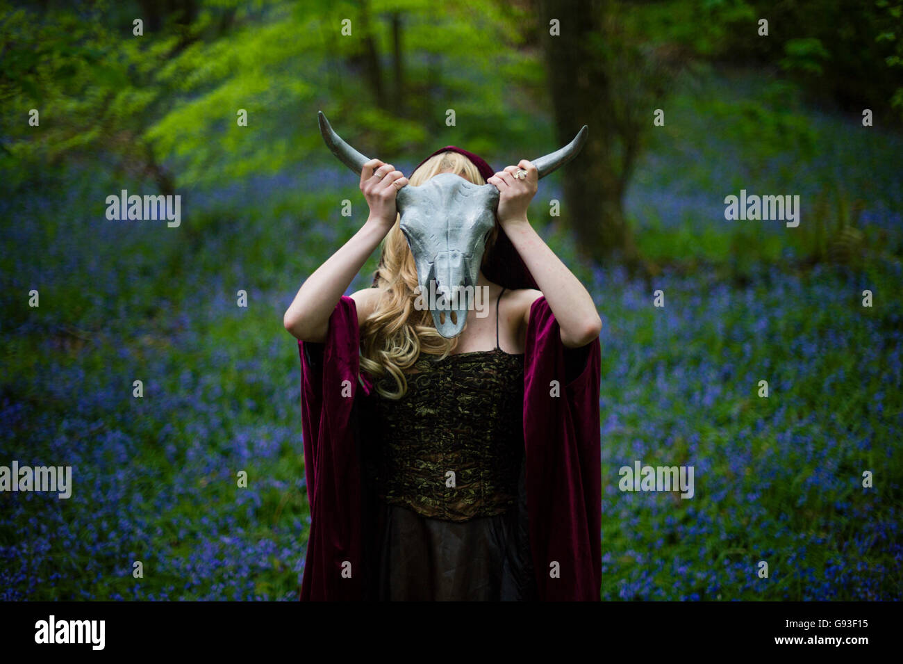 Eine junge Frau, die Modellierung für ein Fantasy-Makeover "Game of Thrones" Fotografie im freien Stil: Göttin / Priesterin / Jägerin im Wald, ein Metall Tiere halten gehörnten Schädel vor ihr Gesicht, UK Stockfoto