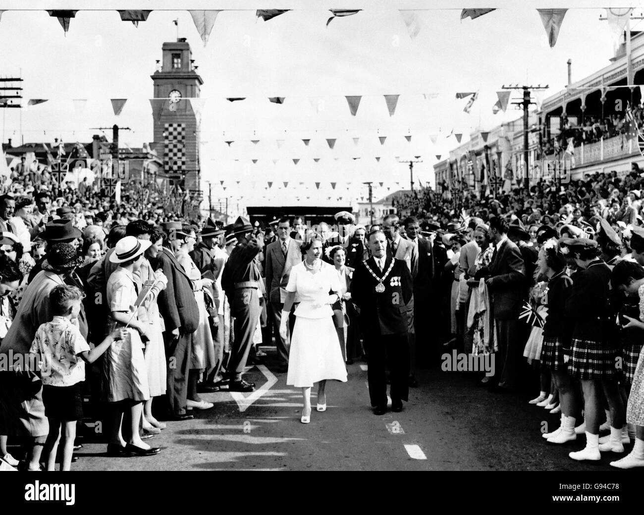 Massen jubelender Menschen drängen nach vorne, während die Königin und der Herzog von Edinburgh (hinten gesehen) von der Plattform, die in der Hauptstraße errichtet wurde, nach ihrem bürgerlichen Empfang in Stratford zurück zum Bahnhof gehen. Stockfoto