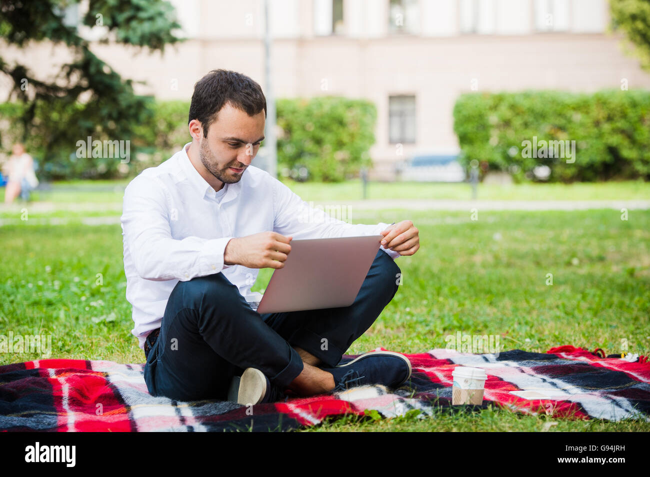 Man arbeitet mit Laptop im Park. Outdoor, Kerl aussehen herausgefordert und denken Stockfoto