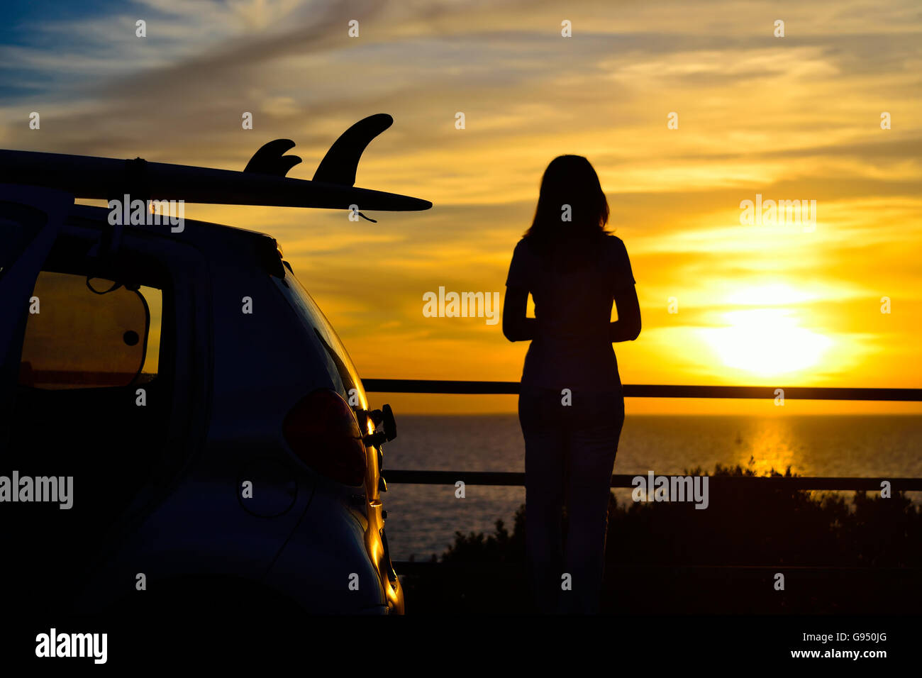 Surfbrett auf einem Auto-Dach am Meer bei Sonnenuntergang Stockfoto