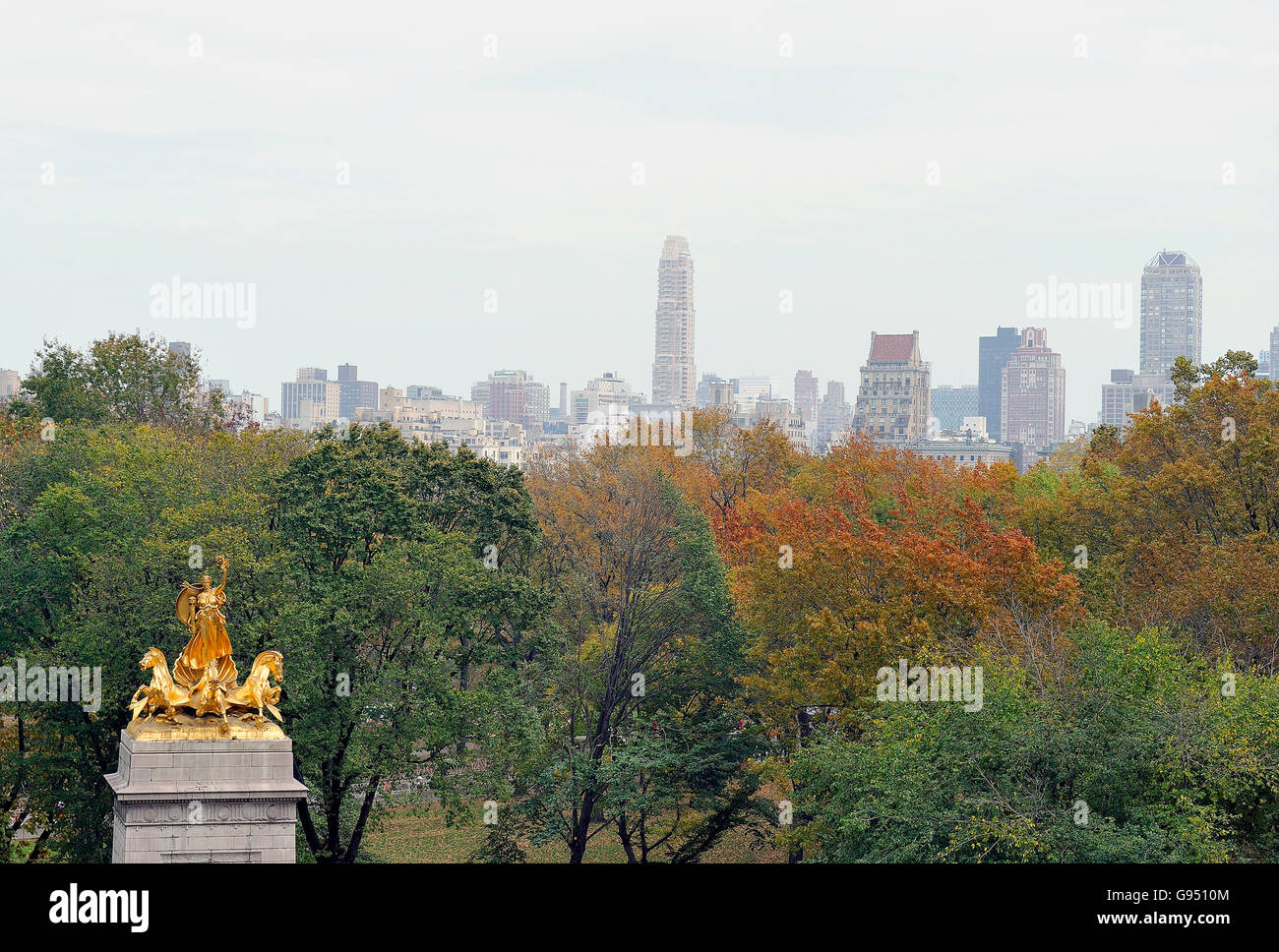 Morgenlicht auf der westlichen Seite des Central Park mit der Skyline und der Spitze des Denkmals am Eingang des Händlers Tor Stockfoto