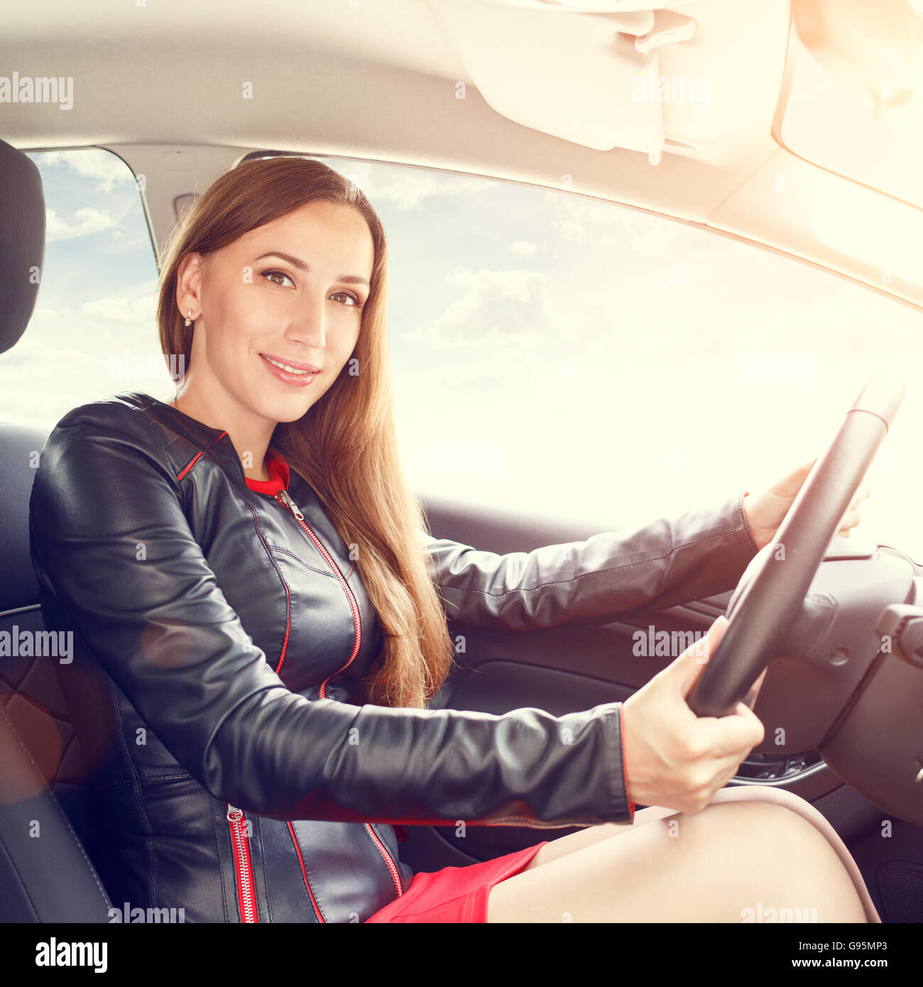 Junge Dame im roten Kleid, ein Auto zu fahren. Driving School Hintergrund Stockfoto
