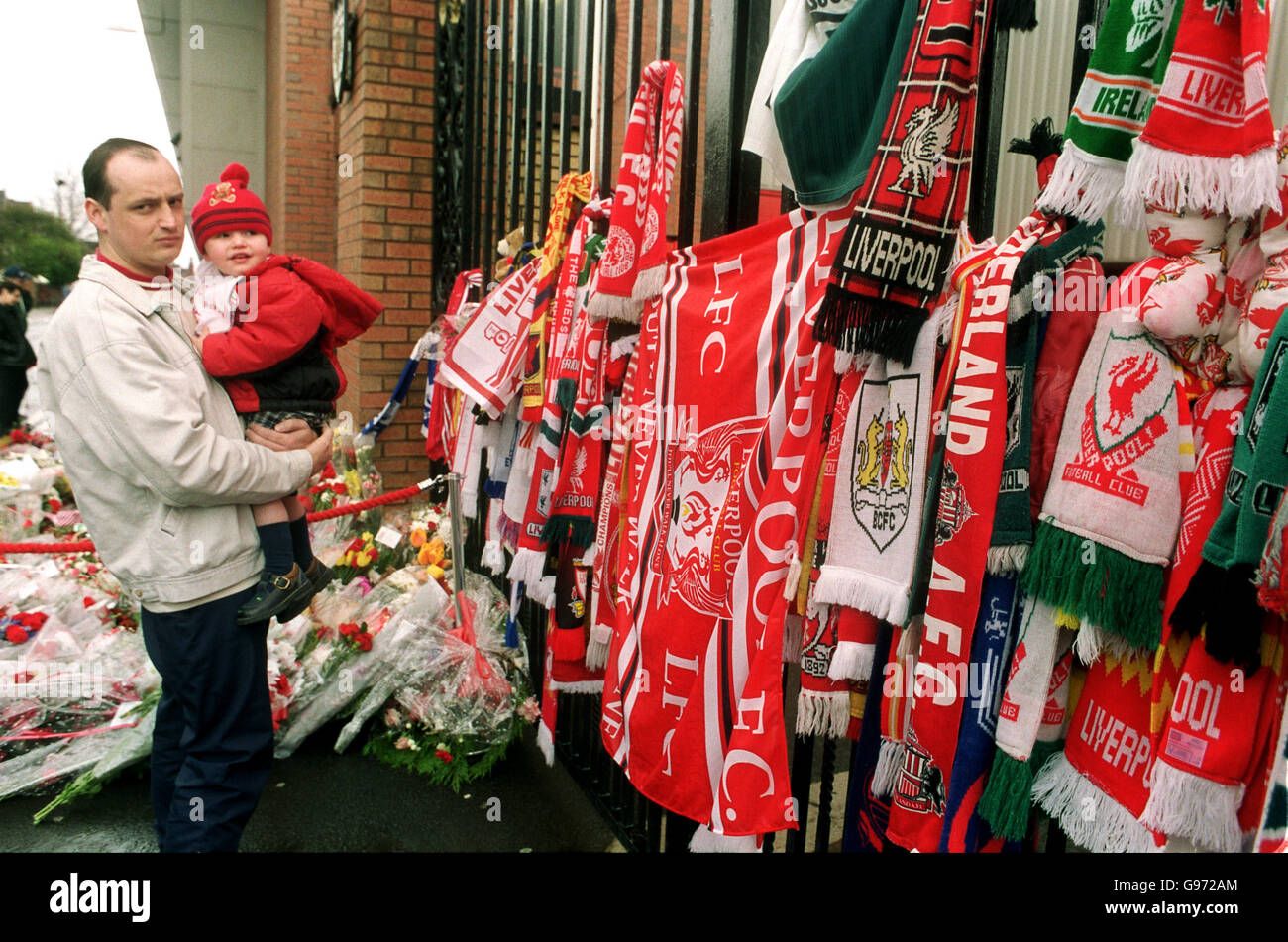 Ein Liverpudlian und sein Sohn schauen sich das genauer an Die Hunderte von Schals an die Tore gebunden Stockfoto
