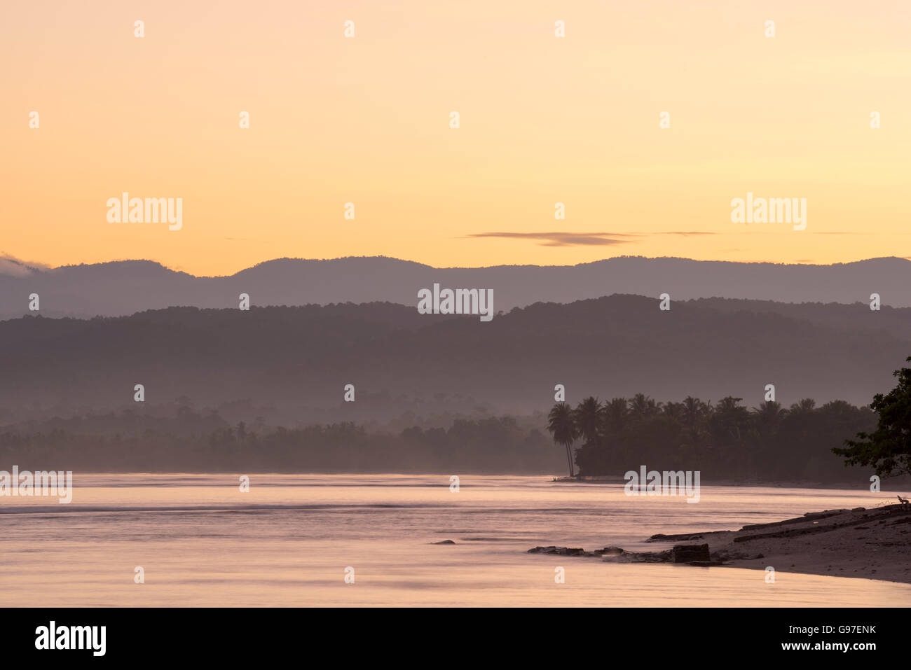 Wilde Naturlandschaft von üppigen Strandküste mit Bäumen und Hügeln Silhouetten in den Horizont. Stockfoto