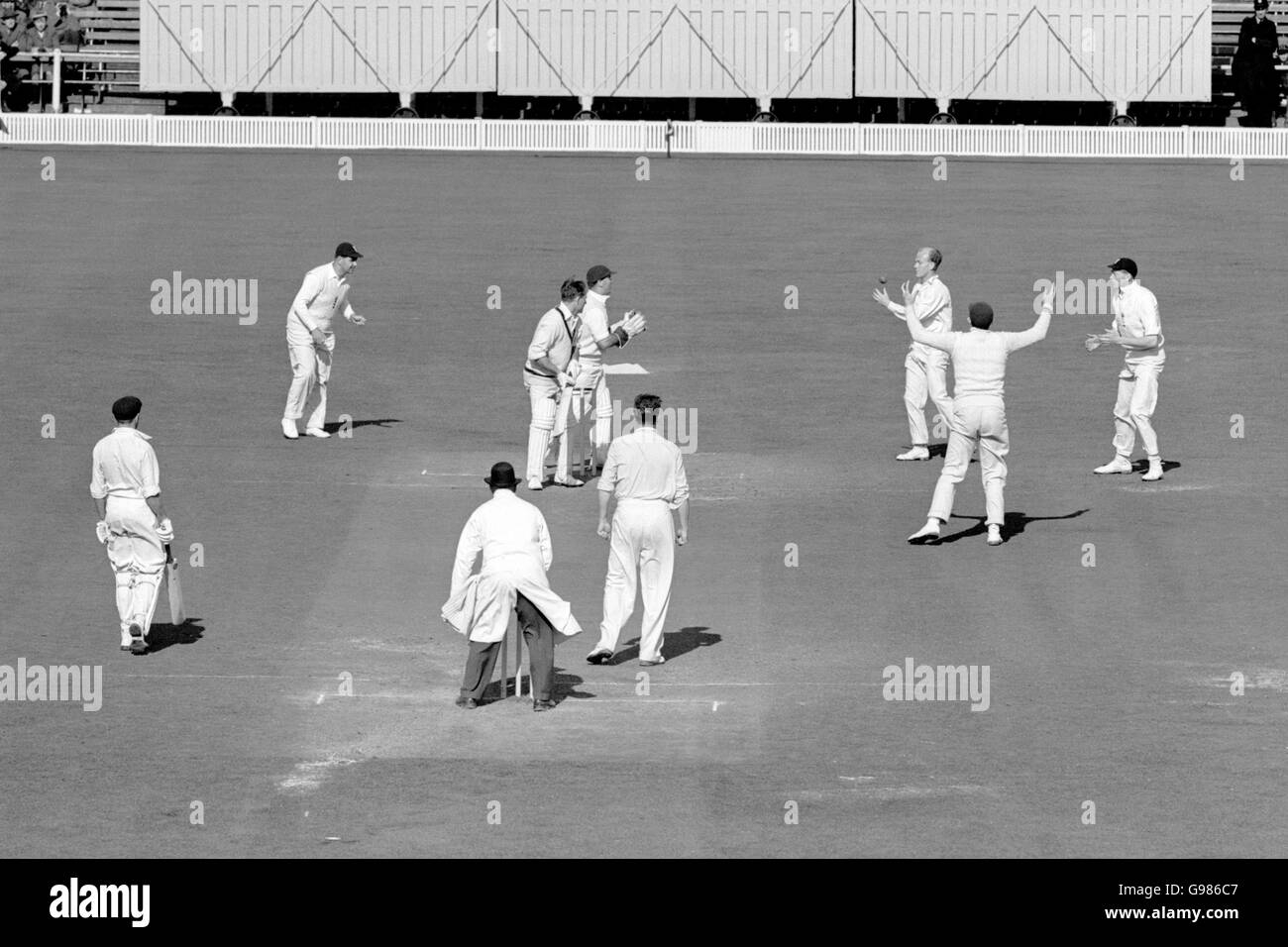 Cricket - The Ashes - Vierter Test - England gegen Australien - Old Trafford - Fünfter Tag. Der Australier Ray Lindwall (oben c) wird von Englands Tony Lock (dritte r) beim Bowling von Jim Laker (neben dem Schiedsrichter) gefangen Stockfoto