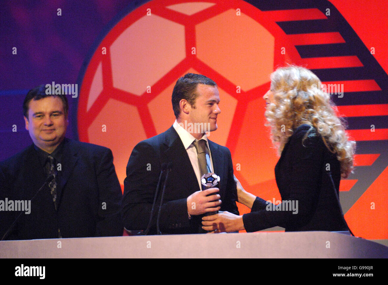 Manchester United und Wayne Rooney aus England erhalten den Young Player of the Year Award der FIFPro Academy von Jerry Hall (r), als Eamonn Holmes (l) anschaut.bei den Mastercard FIFPro World XI Player Awards 2005, die für Sky One aufgenommen wurden. Stockfoto