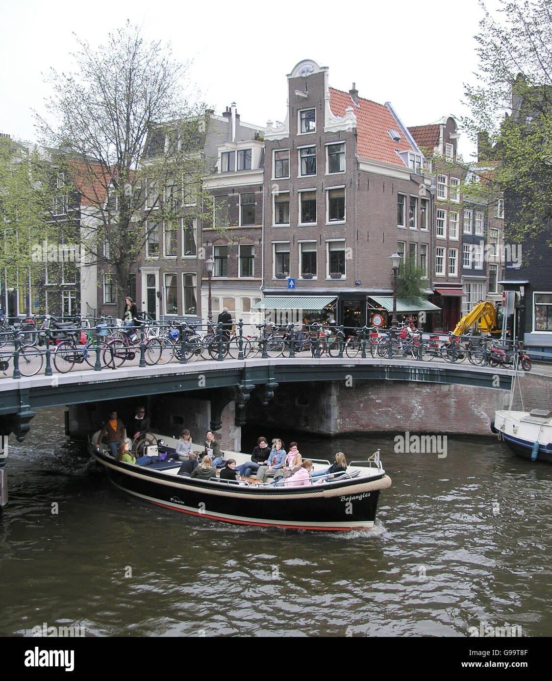 Ausflugsboote fahren durch Grachten in Amsterdam. Stockfoto