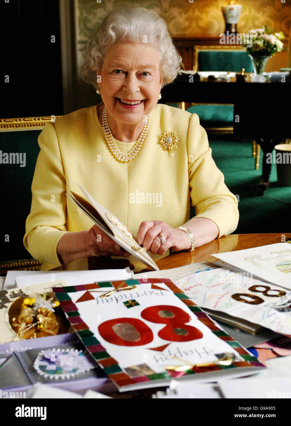 Königin Elizabeth II. Sitzt im Regency Room des Buckingham Palace in London, während sie sich einige der Karten ansieht, die ihr zu ihrem 80. Geburtstag zugeschickt wurden. Stockfoto