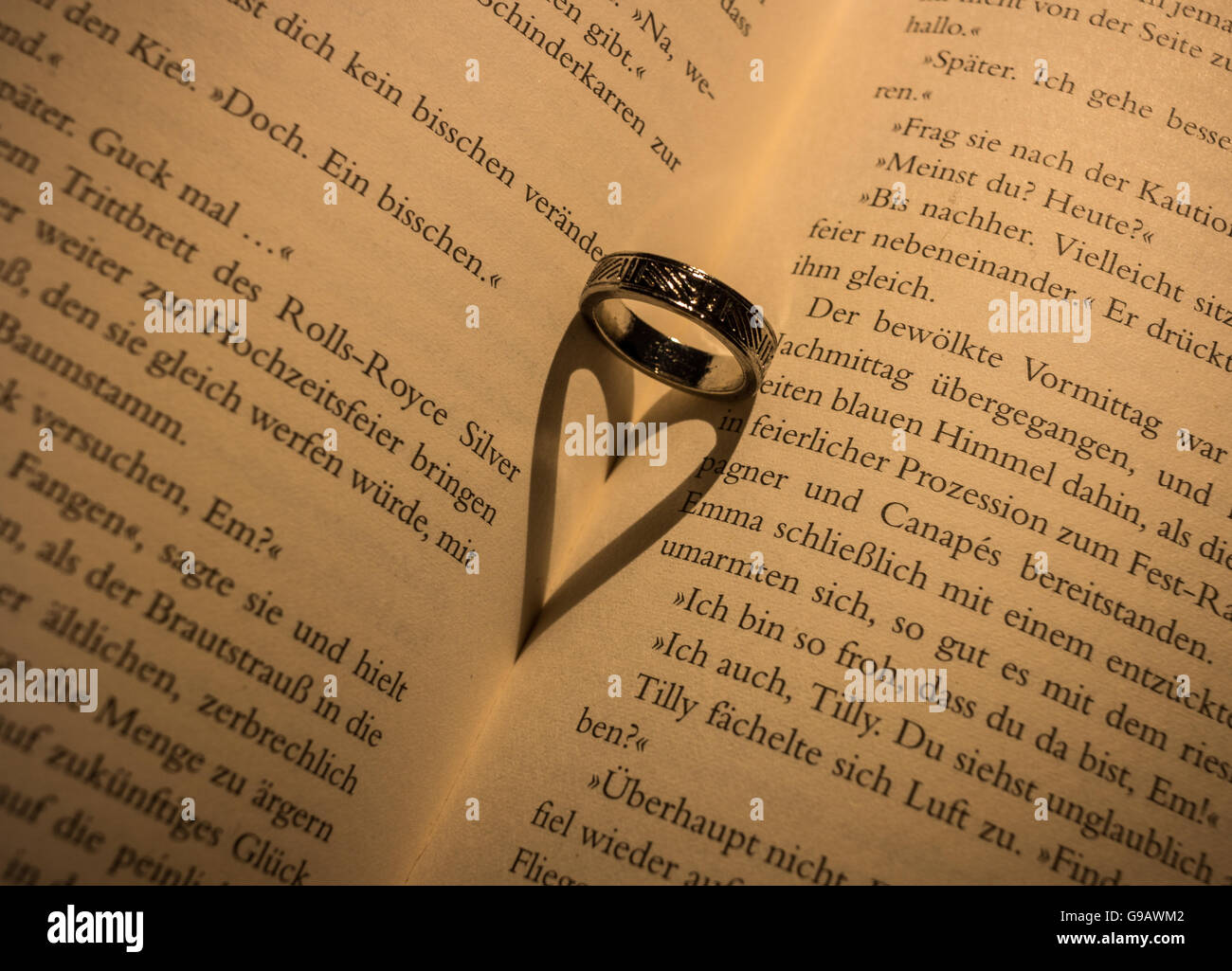 Ring wirft einen herzförmigen Schatten in Buch. Stockfoto