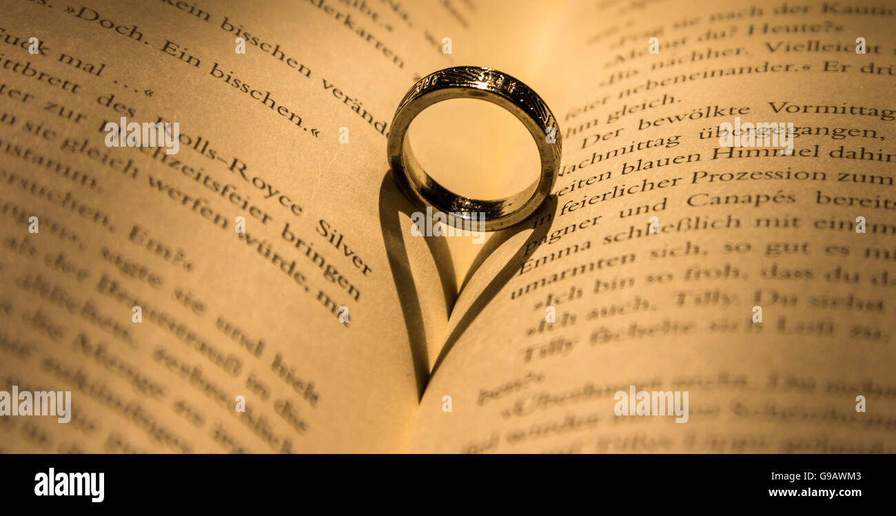 Ring wirft einen herzförmigen Schatten in Buch. Stockfoto
