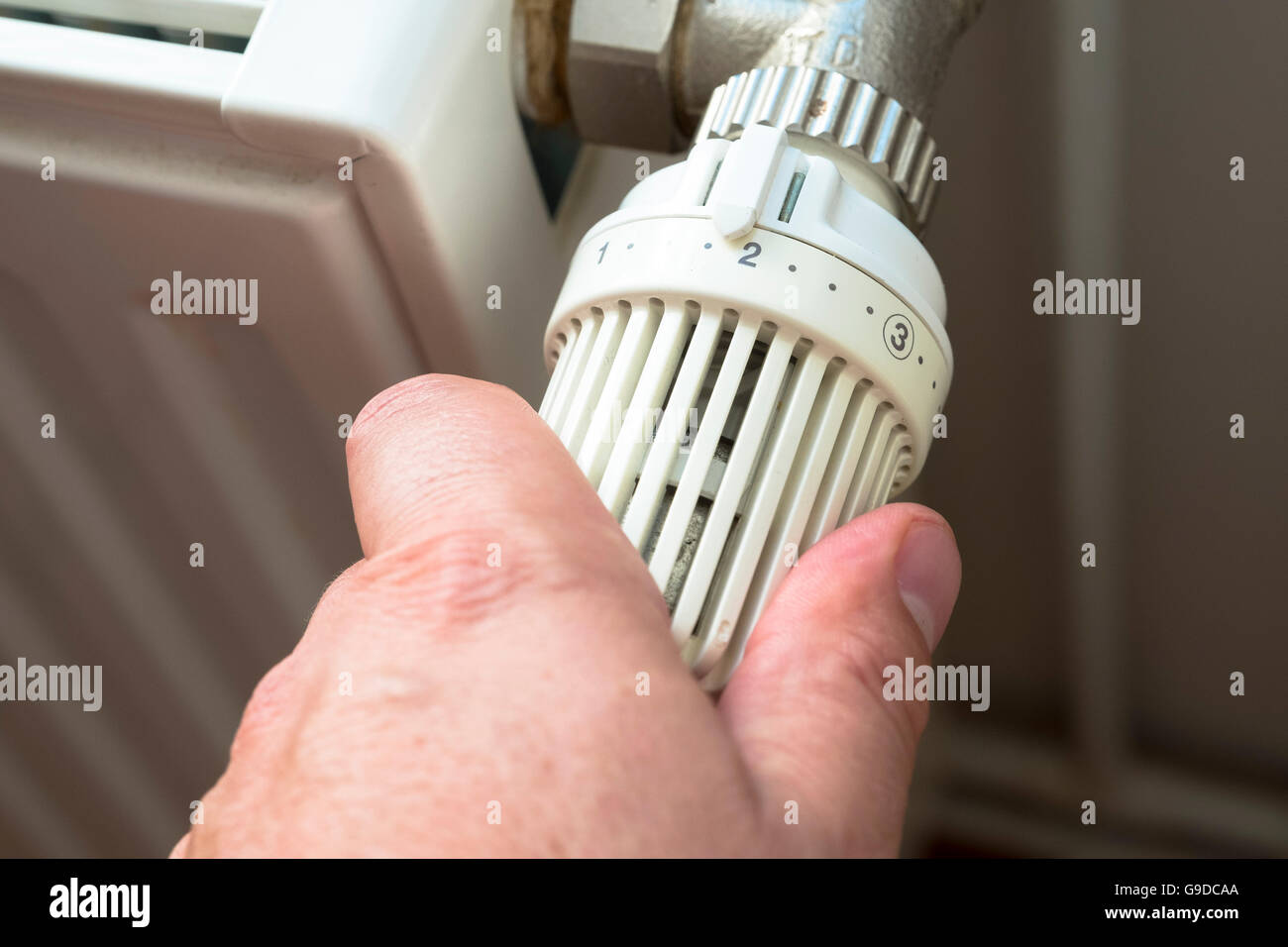 Mann auf Gas betriebene Zentralheizung Heizkörper Thermostat herunterdrehen, um Energie zu sparen Stockfoto Mann auf Gas betriebene Zentralheizung Heizkörper Thermostat herunterdrehen, um Energie zu sparen Stockfoto