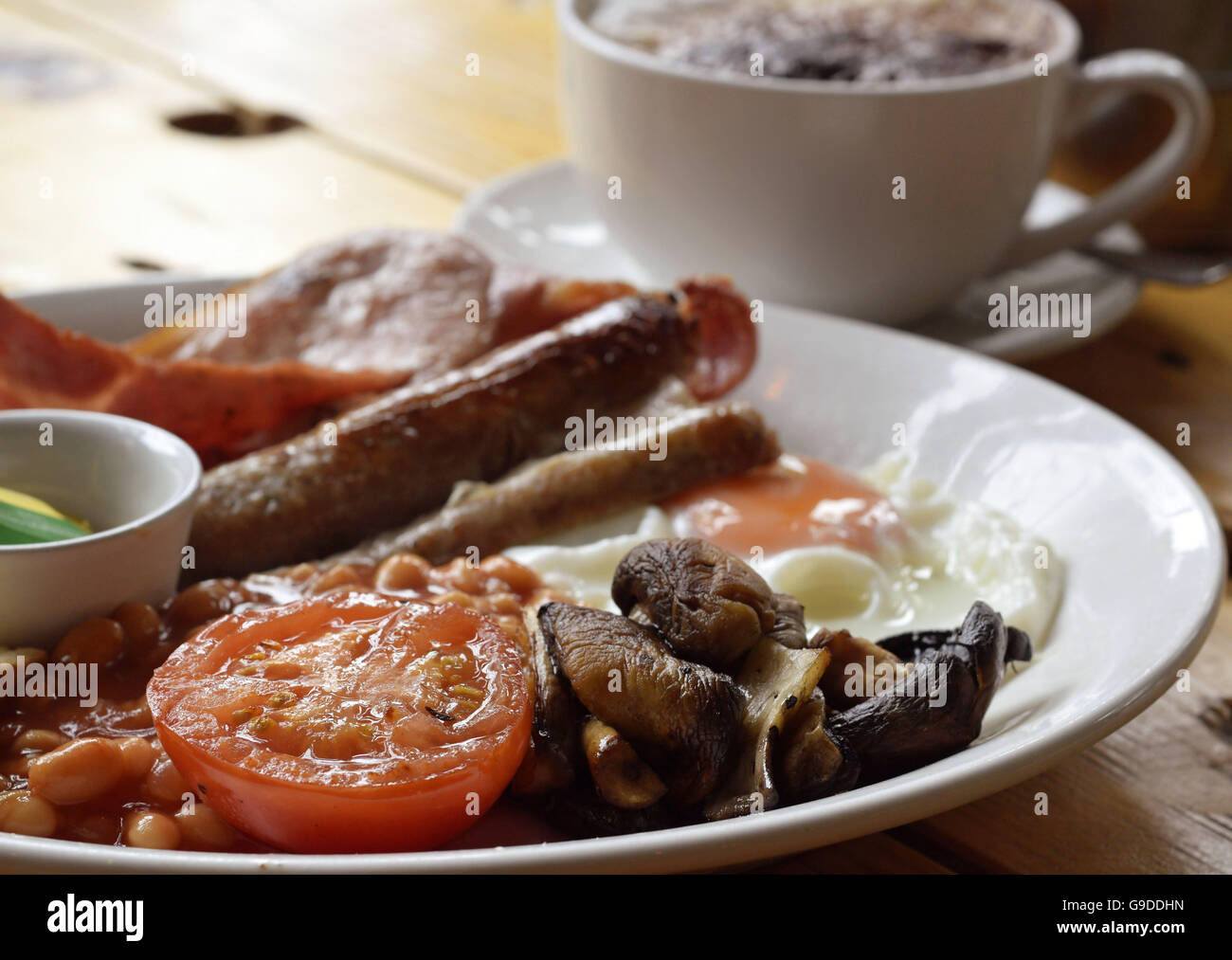 Komplettes warmes Frühstück mit Speck, Wurst, Pilzen und Tomaten Stockfoto