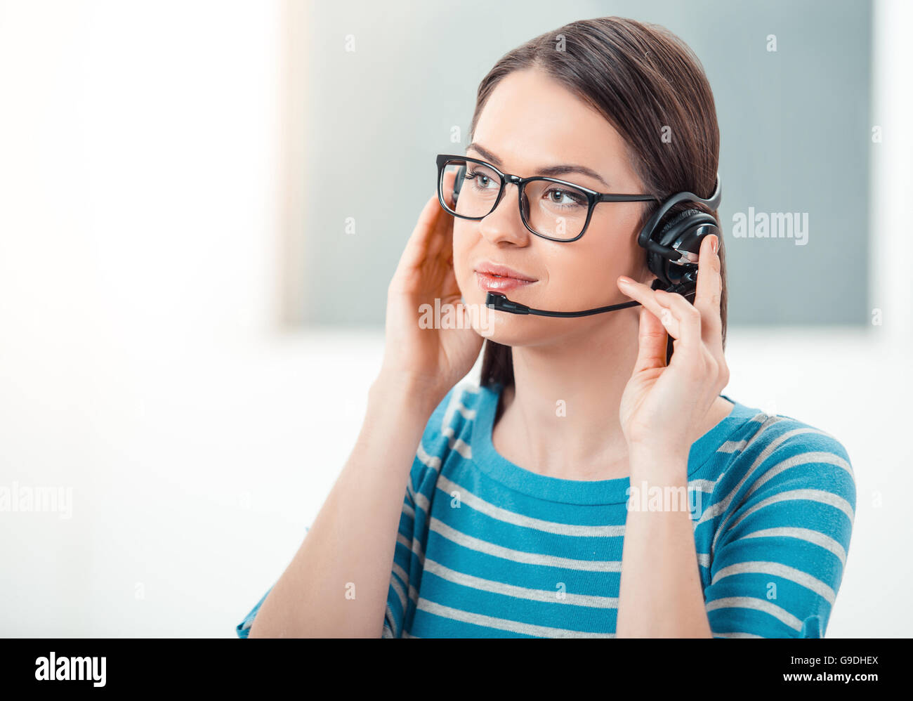 Schöne junge call Center-Betreiber in modernen Büros mit großen Fenster. Frau mit Brille und Kopfhörer Stockfoto