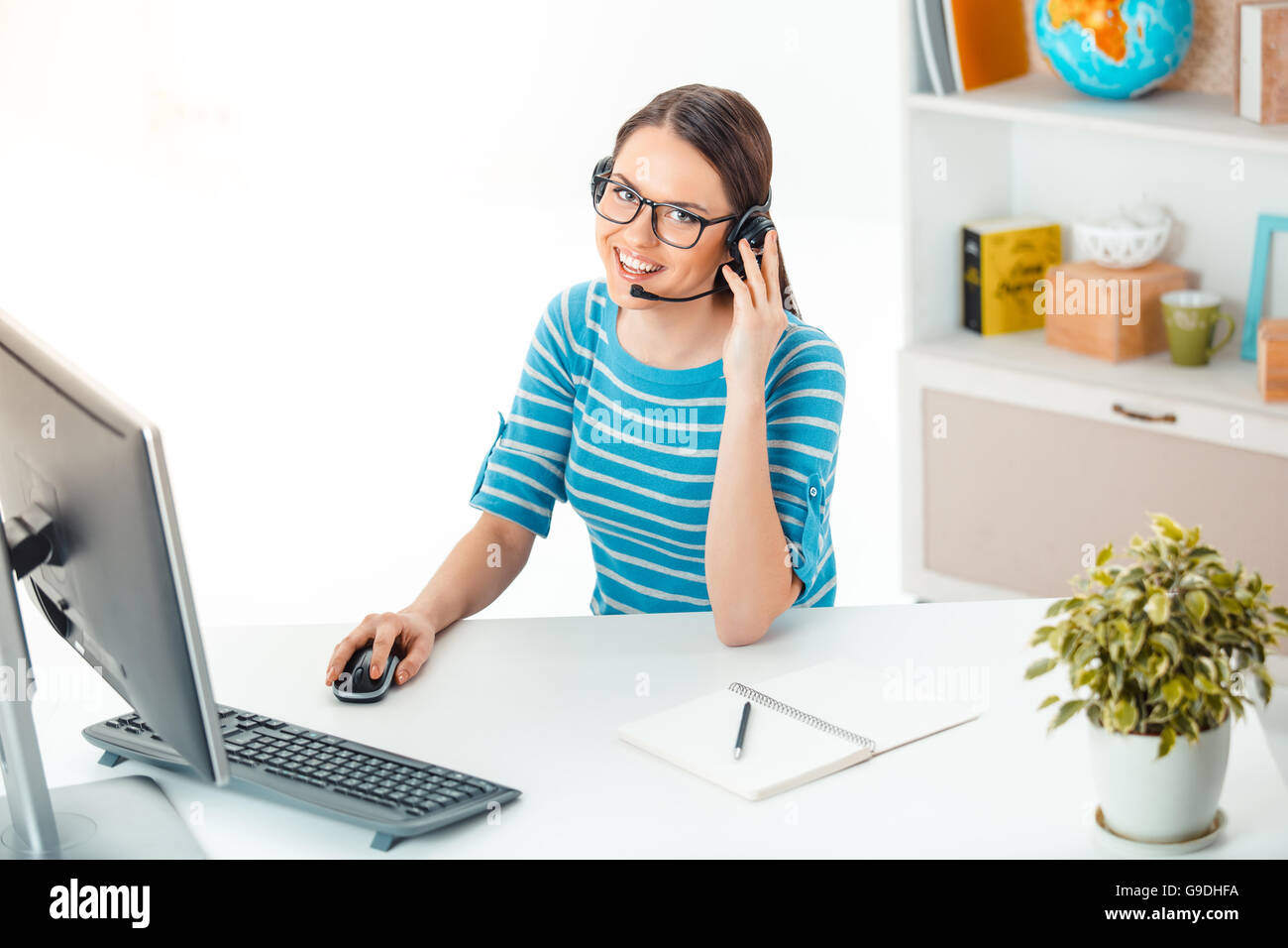Schöne junge call Center-Betreiber in modernen Büros mit Schrank voll von Büromaterial. Frau mit Brille und Kopfhörer Stockfoto