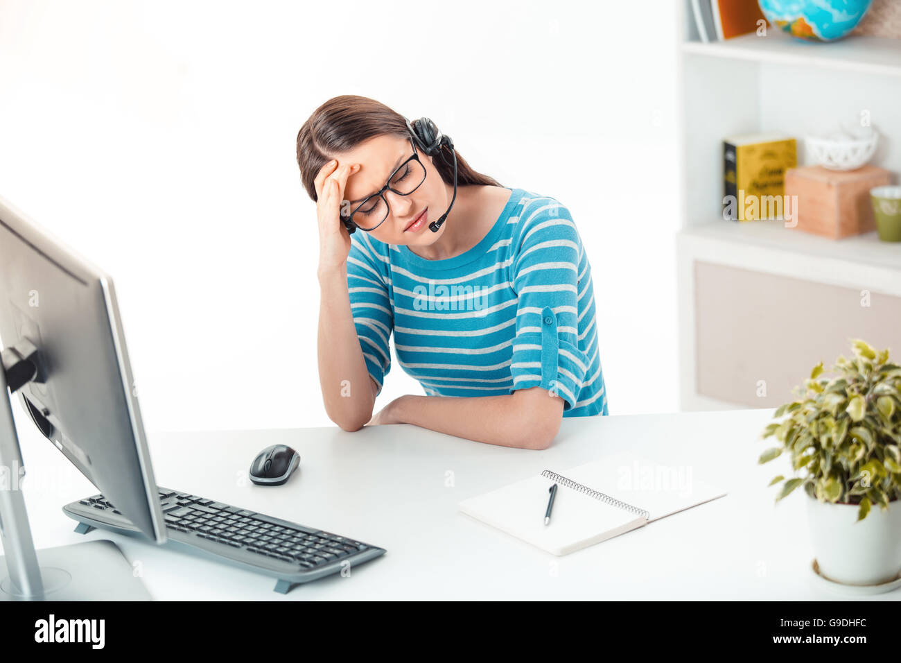 Schöne junge call Center-Betreiber in modernen Büros mit Schrank voll von Büromaterial. Frau mit Brille und Kopfhörer Stockfoto