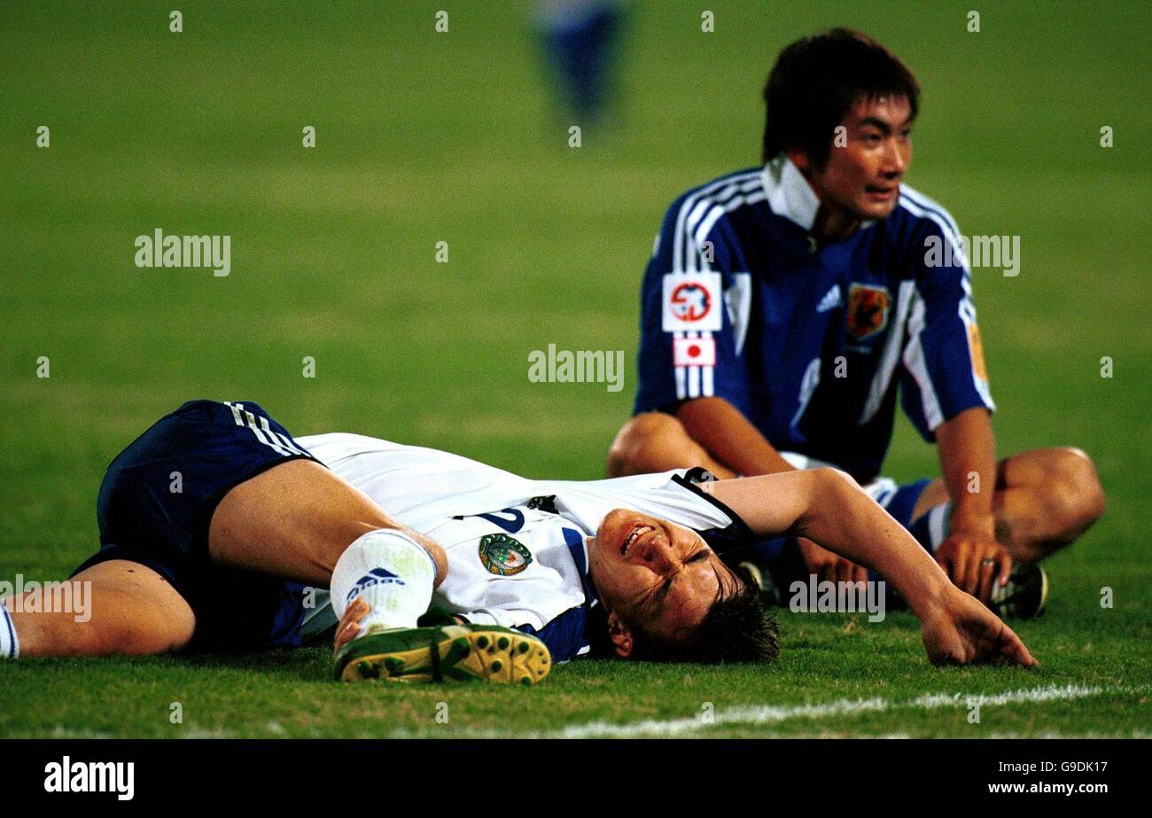 Fußball - Asienmeisterschaft 2000 - Gruppe C - Japan gegen Usbekistan. Akinori Nishizawa aus Japan (r) sitzt neben dem verletzten Bakhtiyor Aschuramatov aus Usbekistan (l) Stockfoto